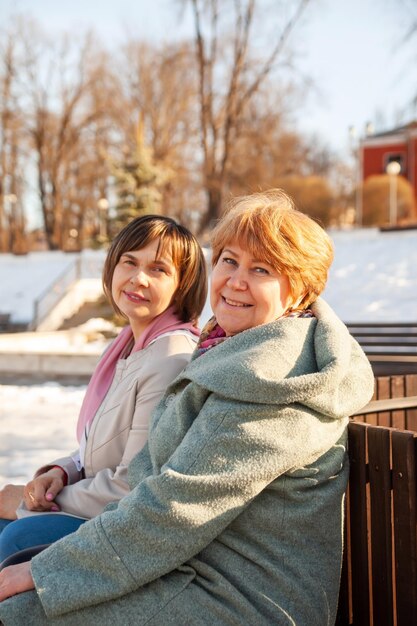 Donne anziane casuali contemplative sedute su una panchina in primavera parkxDxAxDxA