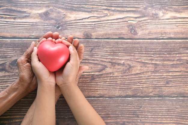 donne anziane e bambino che tiene il cuore rosso da vicino