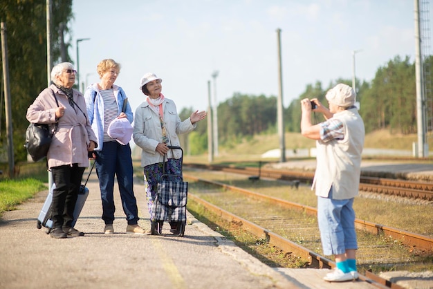 Donne anziane sorridenti scattano una foto su una piattaforma in attesa di un treno per viaggiare