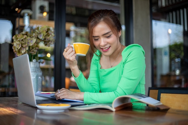 Donne asiatiche che leggono libri e sorridono e si rilassano felici in una caffetteria dopo aver lavorato con successo