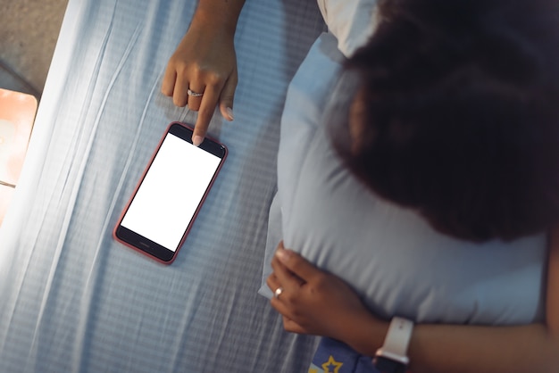 Donne asiatiche che utilizzano lo smart phone sul letto prima di dormire la notte.