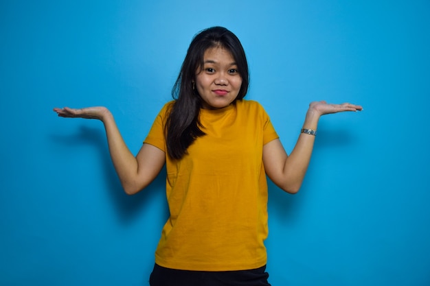 Donne asiatiche con sfondo blu isolato guardano la telecamera e fanno un gesto confuso