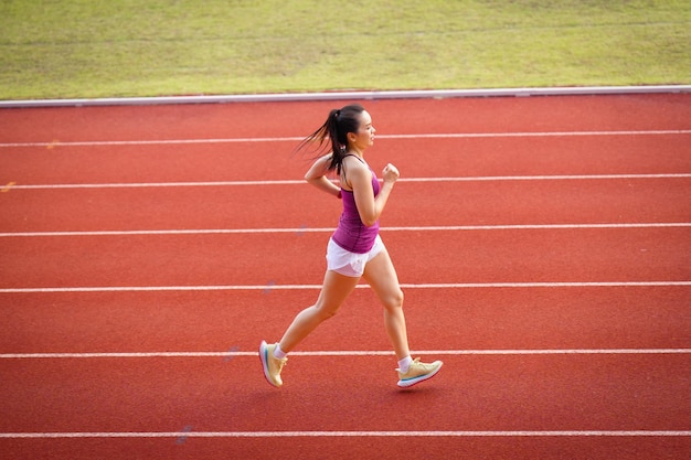 Donne asiatiche di mezza età in esecuzione durante la mattina di sole sulla pista dello stadio