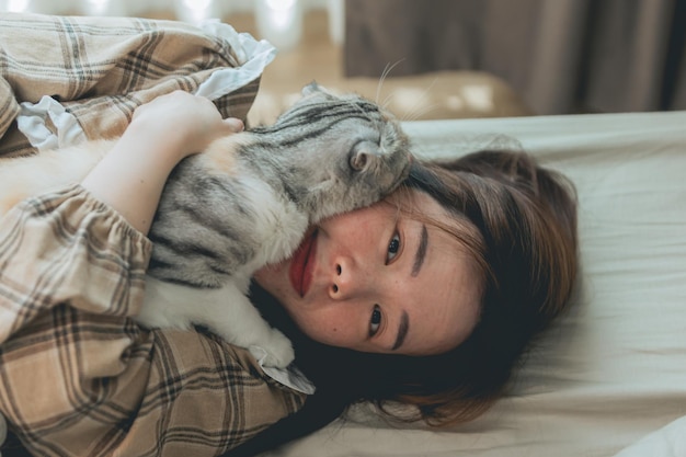 Donne asiatiche felici di sorriso che abbracciano un gatto carino a casa.