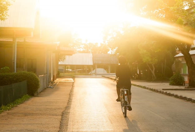 Donne asiatiche in bicicletta sulla strada nella luce della sera a soli