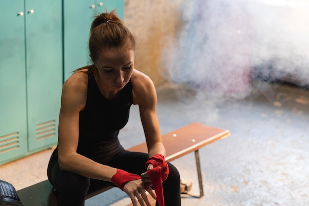 Donne autodifesa ragazza potere donna combattente che si prepara per la lotta avvolgendo le mani con impacchi di boxe rossi