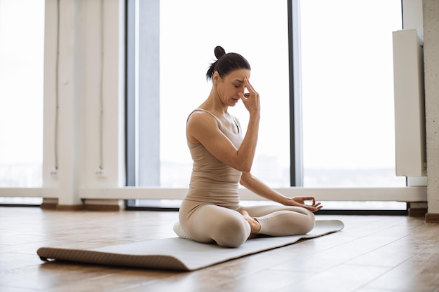 Donne caucasiche atletiche mature in abiti sportivi che respirano in posizione di asana