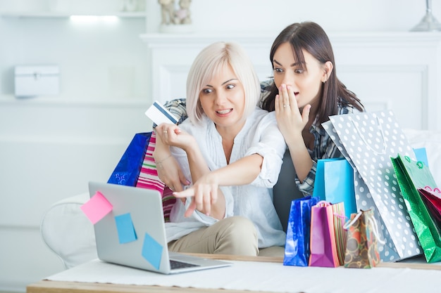 Donne che fanno acquisti online. Femmina al laptop con borse della spesa