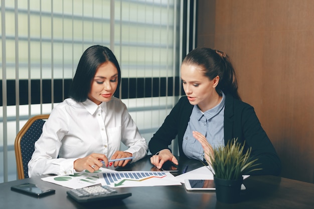 Donne che guardano i documenti finanziari in computer portatile la tavola