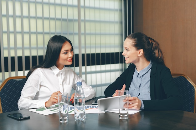 Donne che guardano i documenti finanziari in computer portatile la tavola