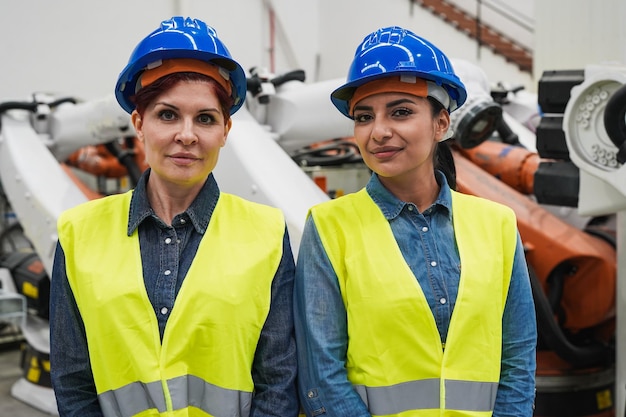 Donne che lavorano all'interno di una fabbrica rocotica che guardano sulla fotocamera Team di ingegneri femminili