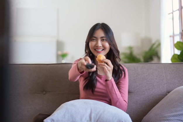 Donne che mangiano pane mentre guardano la tv e cambiano canale con il telecomando nello stile di vita di casa