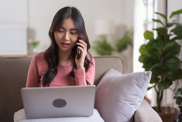 Donne che parlano sullo smartphone e digitano dati aziendali sul laptop mentre lavorano a casa