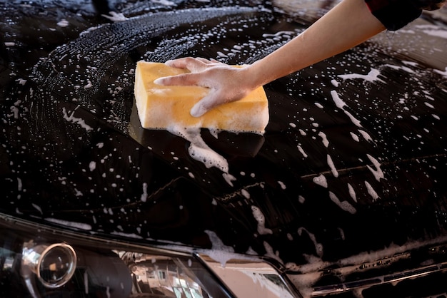 Donne che puliscono l'auto con spugna gialla e schiuma più forti donne che puliscono le auto il suo concetto di persona