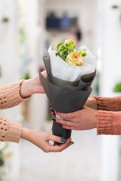 Donne che tengono bouquet di rose e gelsomini in carta artigianale. Consegna addobbi floreali.