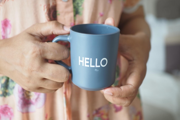 Donne che tengono una tazza di caffè blu con la parola ciao