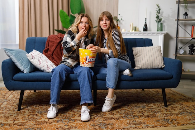 Donne con facce sorprese che guardano la tv a casa sul divano