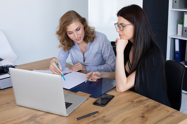 Donne d'affari alla scrivania in ufficio che lavorano insieme sul computer portatile, concetto di lavoro di squadra