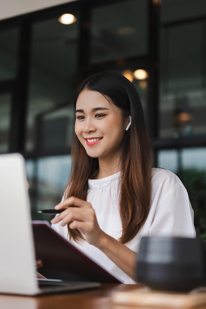 Donne d'affari che ascoltano musica mentre leggono dati sul portatile e controllano i documenti fuori dall'ufficio