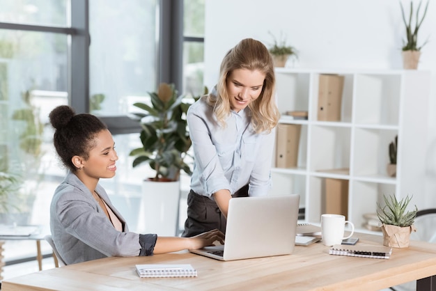 Donne d'affari multietniche che discutono di un nuovo progetto aziendale mentre sono sedute sul posto di lavoro in ufficio