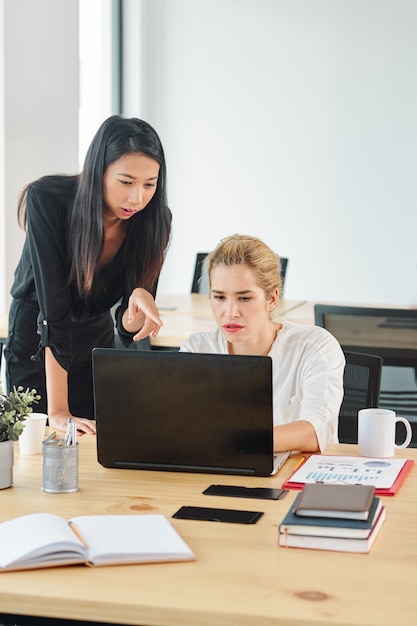 Donne di affari che per mezzo del computer portatile all'ufficio