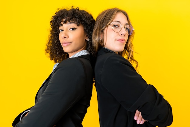 donne di affari schiena contro schiena con le braccia incrociate guardando la fotocamera