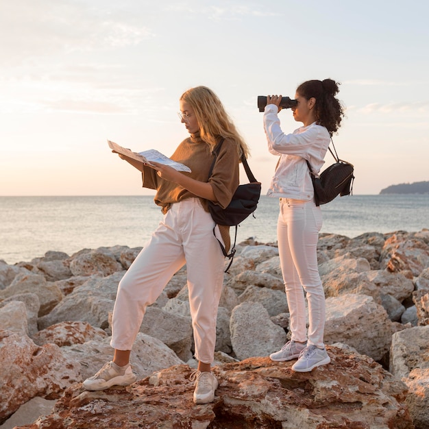 Donne di vista laterale con mappa e binocolo