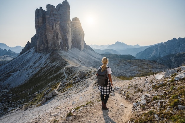 Donne escursionista con zaino godendosi le Tre Cime di Lavaredo durante il tramonto Dolomiti Italia