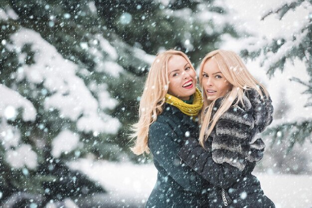 Donne felici che camminano nella foresta il giorno d'inverno