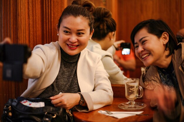 Donne felici che parlano di selfie usando il telefono in un ristorante