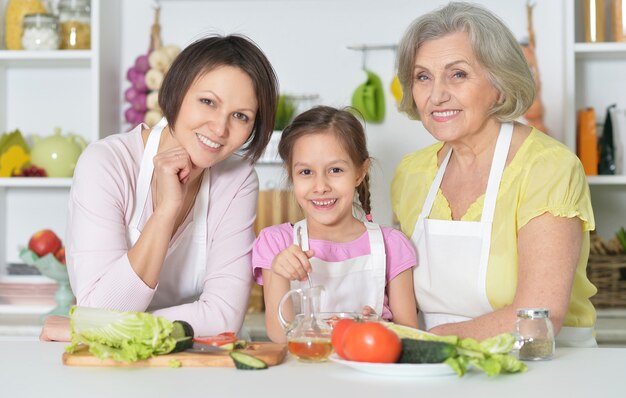 Donne felici con una bambina che cucina in cucina