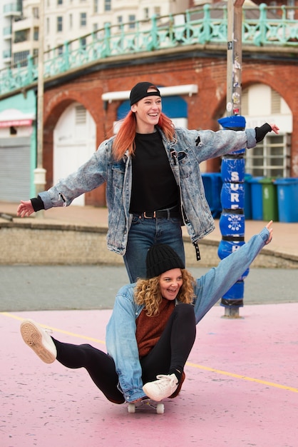 Donne felici del colpo pieno con lo skateboard