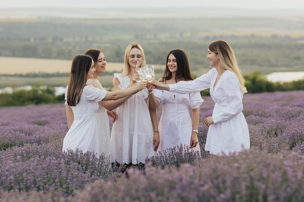 Donne in abiti bianchi che tostano in un campo di lavanda