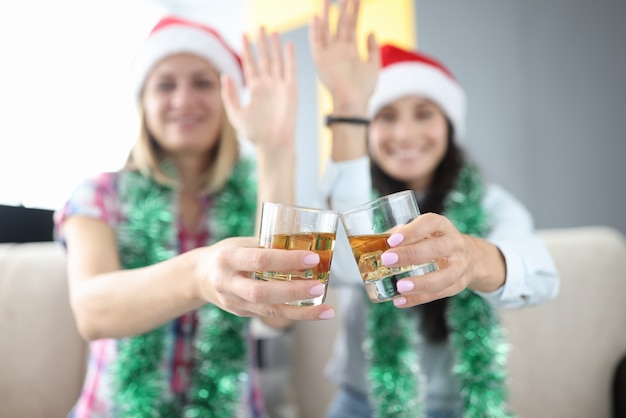 Donne in cappelli di Babbo Natale con bicchieri di whisky