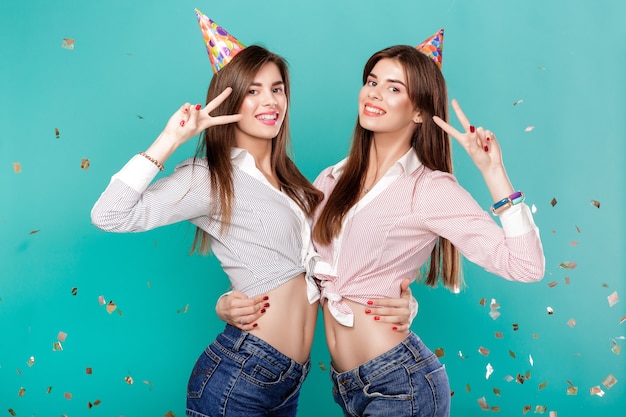 Donne in cappello di compleanno e coriandoli su sfondo blu