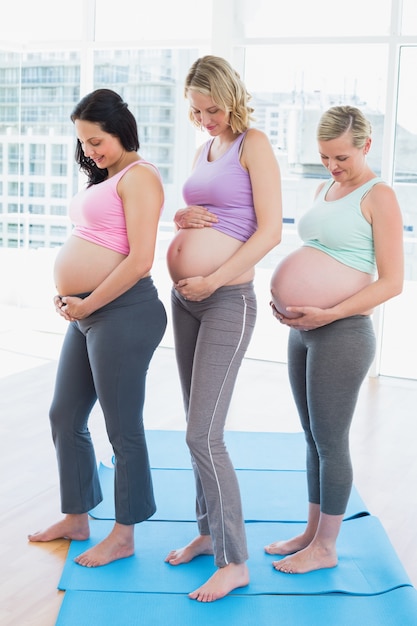 Donne incinte sorridenti che stanno in una fila che esamina gli urti