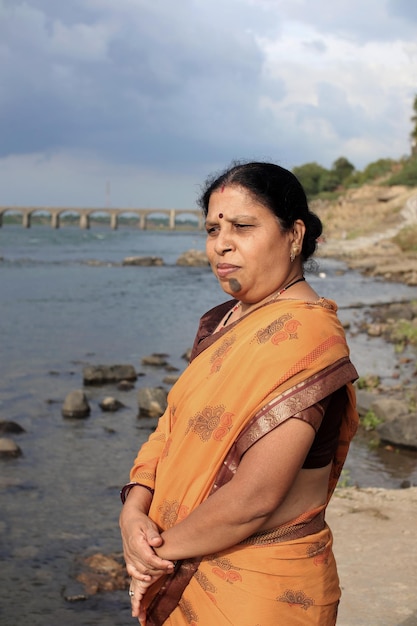 Donne indiane sedute vicino al fiume, donne indiane in saree sedute sulla riva del fiume a guardare il tramonto