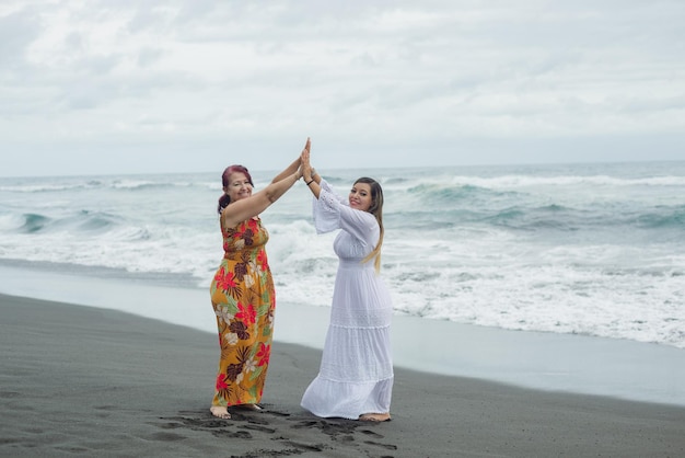 Donne, madre e figlia che si godono il tempo di qualità in spiaggia. Oceano Pacifico, giornata nuvolosa.