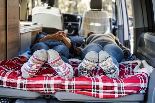 Donne mature che dormono all'interno di un mini van camper che indossano calze calde natalizie - Focus on feet