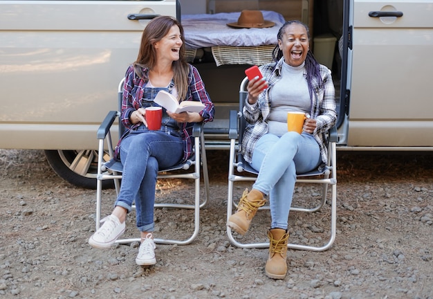 Donne mature multirazziali che si divertono sedute fuori dal camper - Amicizia e vacanza concept