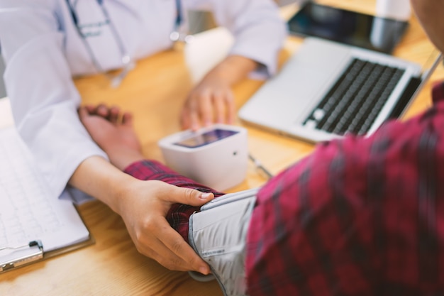 Donne Medici e pazienti stanno discutendo e fanno una misurazione della pressione sanguigna