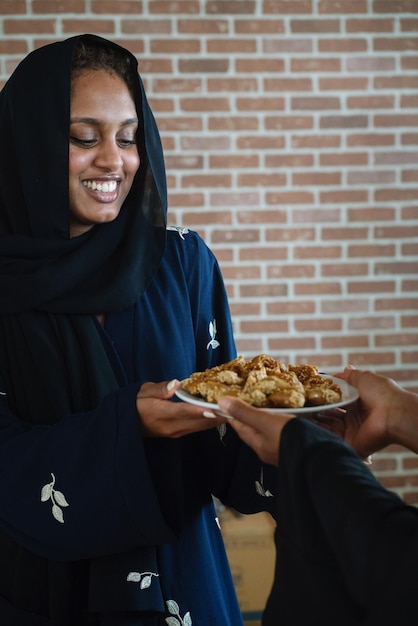 Donne musulmane che indossano abayas regalano e condividono dolci arabi durante il Ramadan