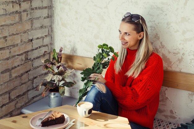 Donne romantiche che si siedono nella caffetteria con fiori in mano e tazza di caffè