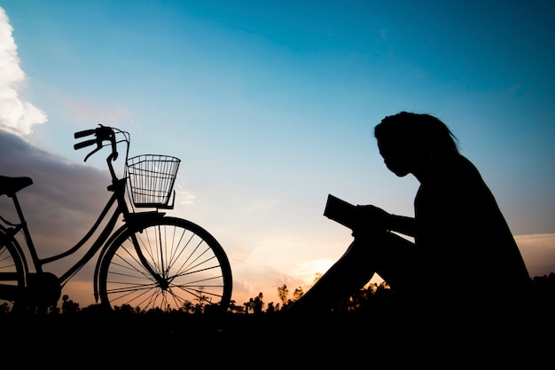 donne silhouette leggendo il libro con la bicicletta