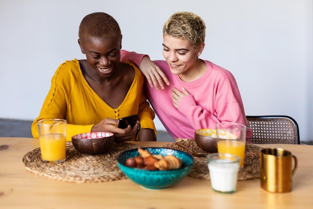 Donne sorridenti che guardano il cellulare mentre mangiano