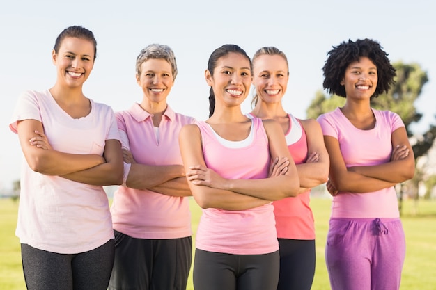 Donne sorridenti che indossano rosa per il cancro al seno con le braccia incrociate