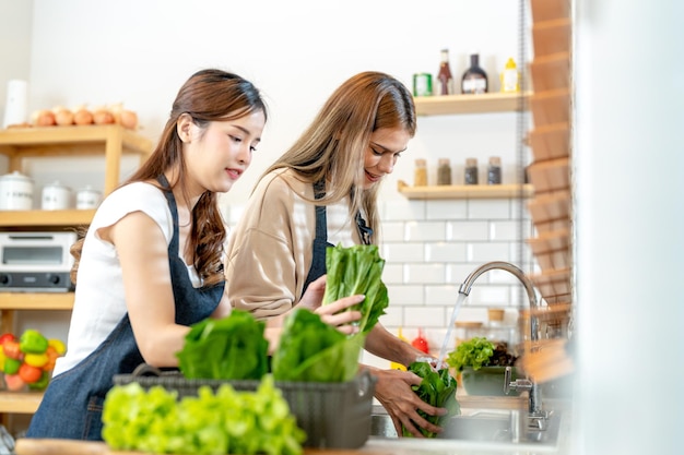 Donne sorridenti che preparano insalata fresca e sana donna in piedi alla dispensa in una bella cucina interna Il cibo dietetico pulito da prodotti e ingredienti locali Mercato fresco