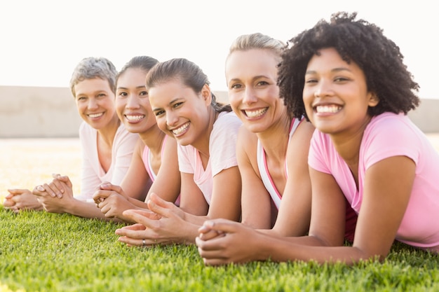 Donne sorridenti che si trovano in una fila e che indossano rosa per il cancro al seno