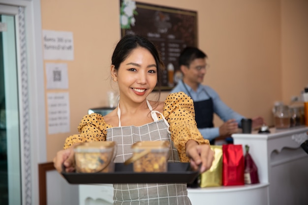 Donne sorridenti che tengono i biscotti nella caffetteria come piccolo imprenditore.