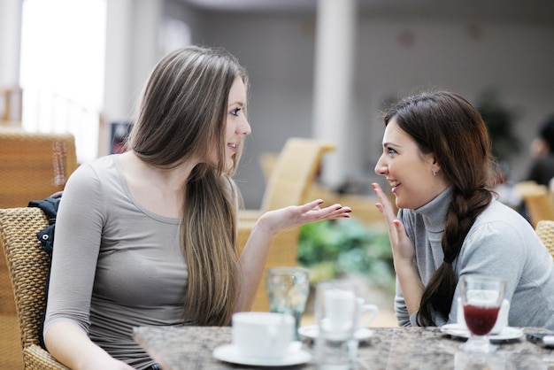 donne sorridenti molto carine che bevono un caffè seduti all'interno nel ristorante caffetteria